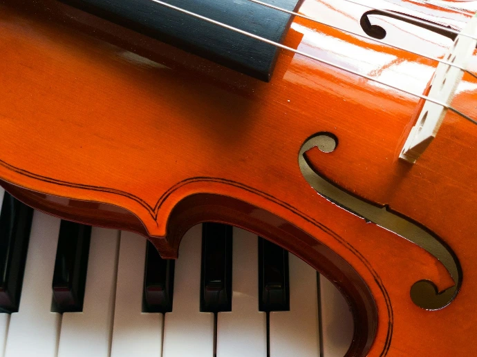 a violin sitting on top of a piano keyboard